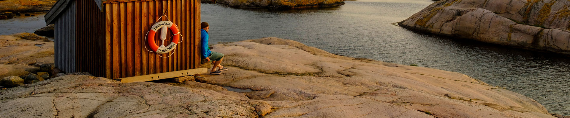 man sitter vid fiskestuga på en holme
