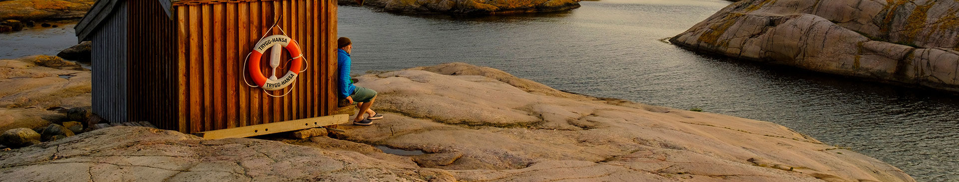 man sitter vid fiskestuga på en holme
